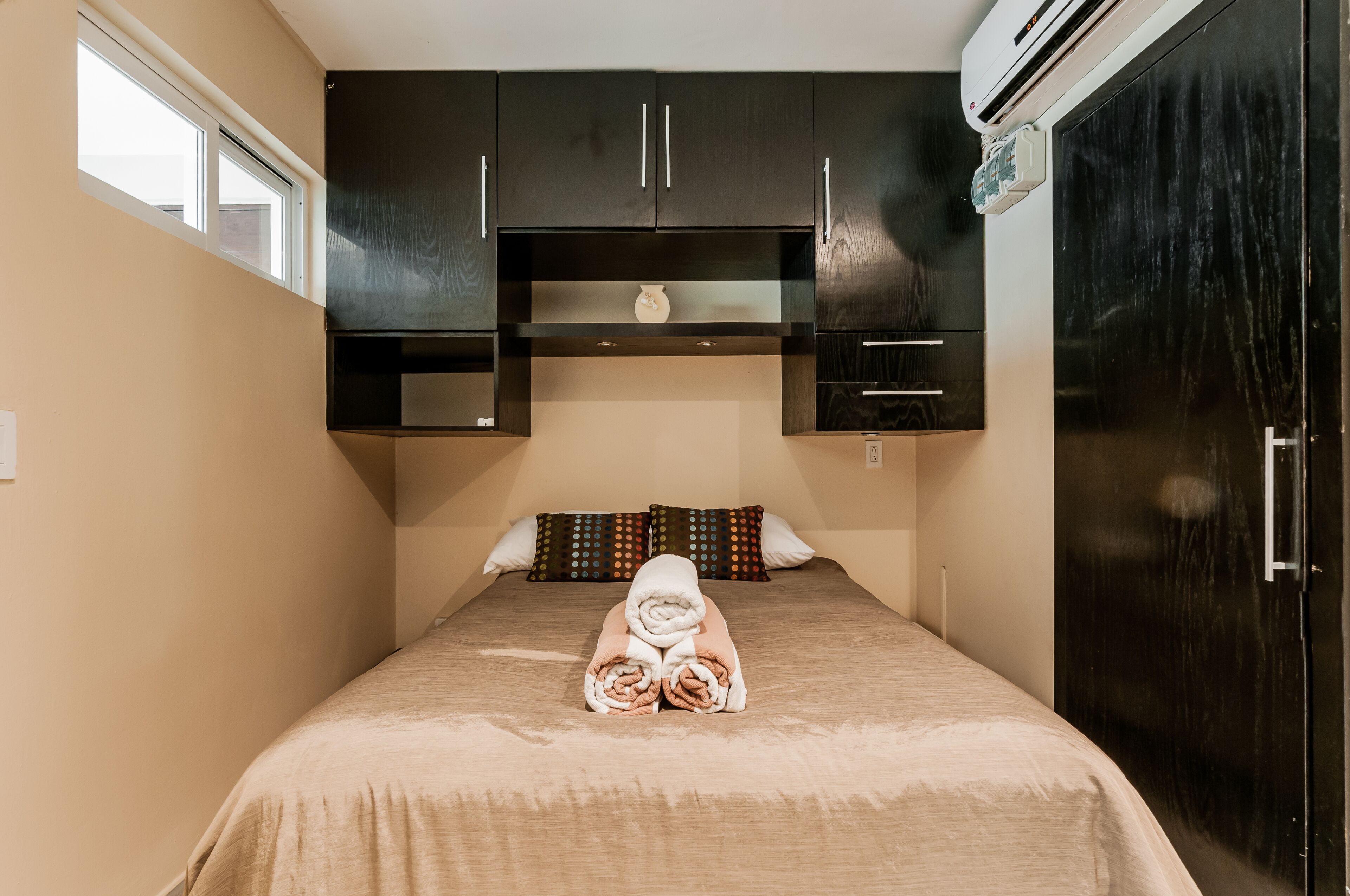 A bedroom with a bed, a wardrobe, and a window.