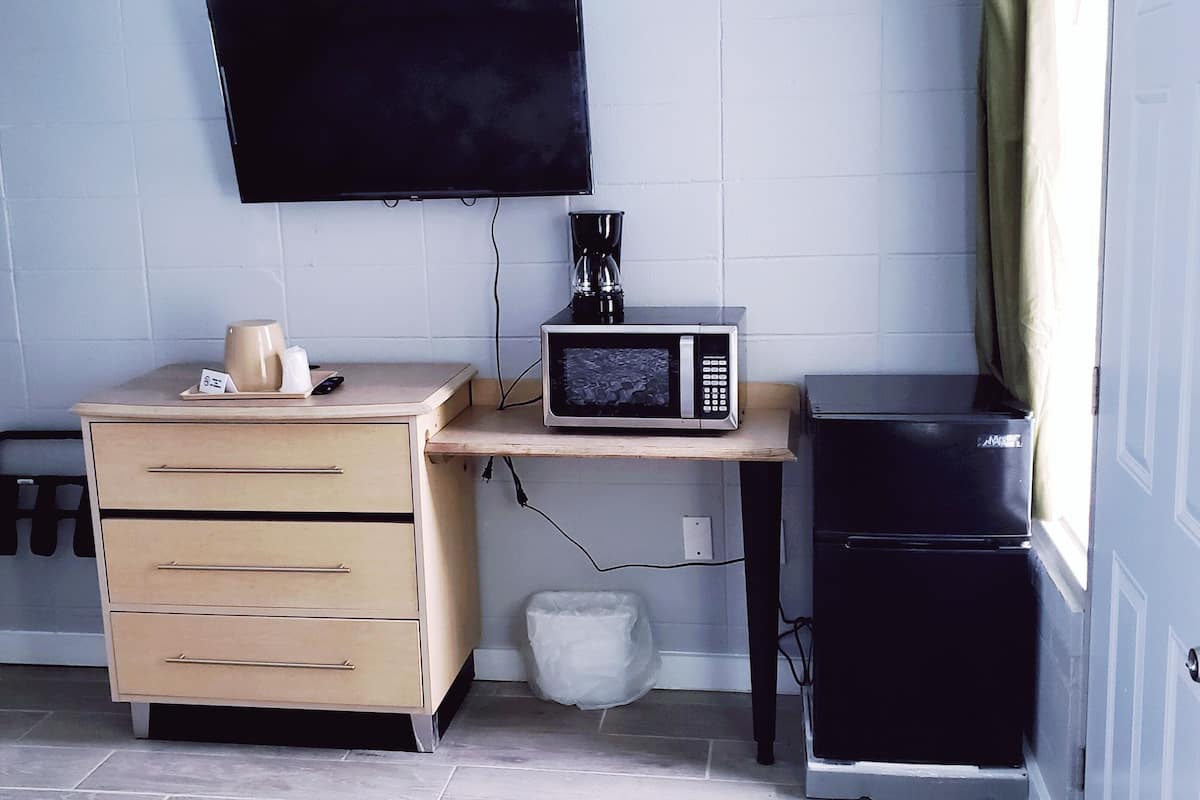 A compact kitchenette with a microwave, a coffee maker, a small refrigerator, and a cabinet with drawers.