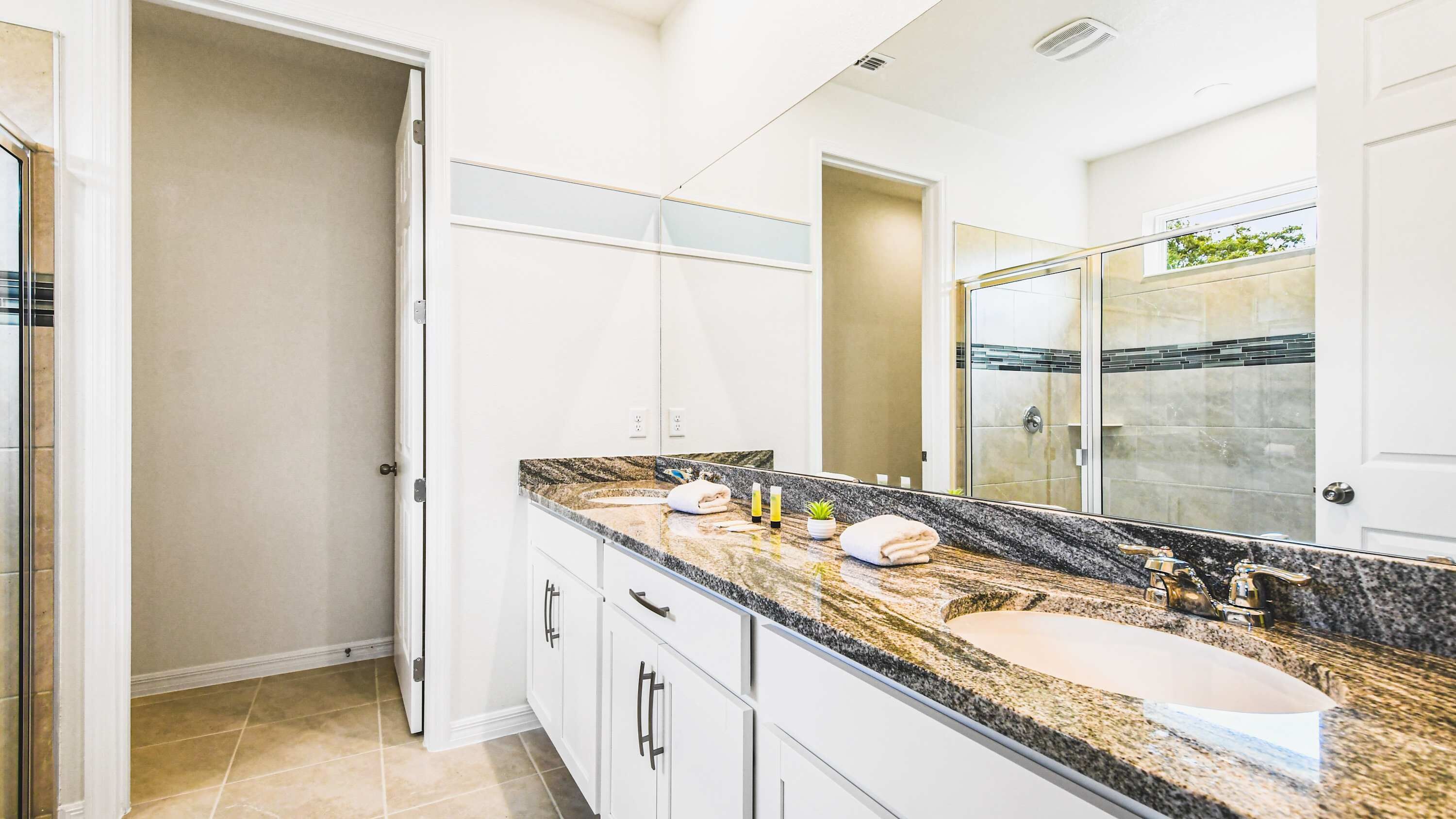 Une salle de bain moderne avec un comptoir en granit, un lavabo et un grand miroir.
