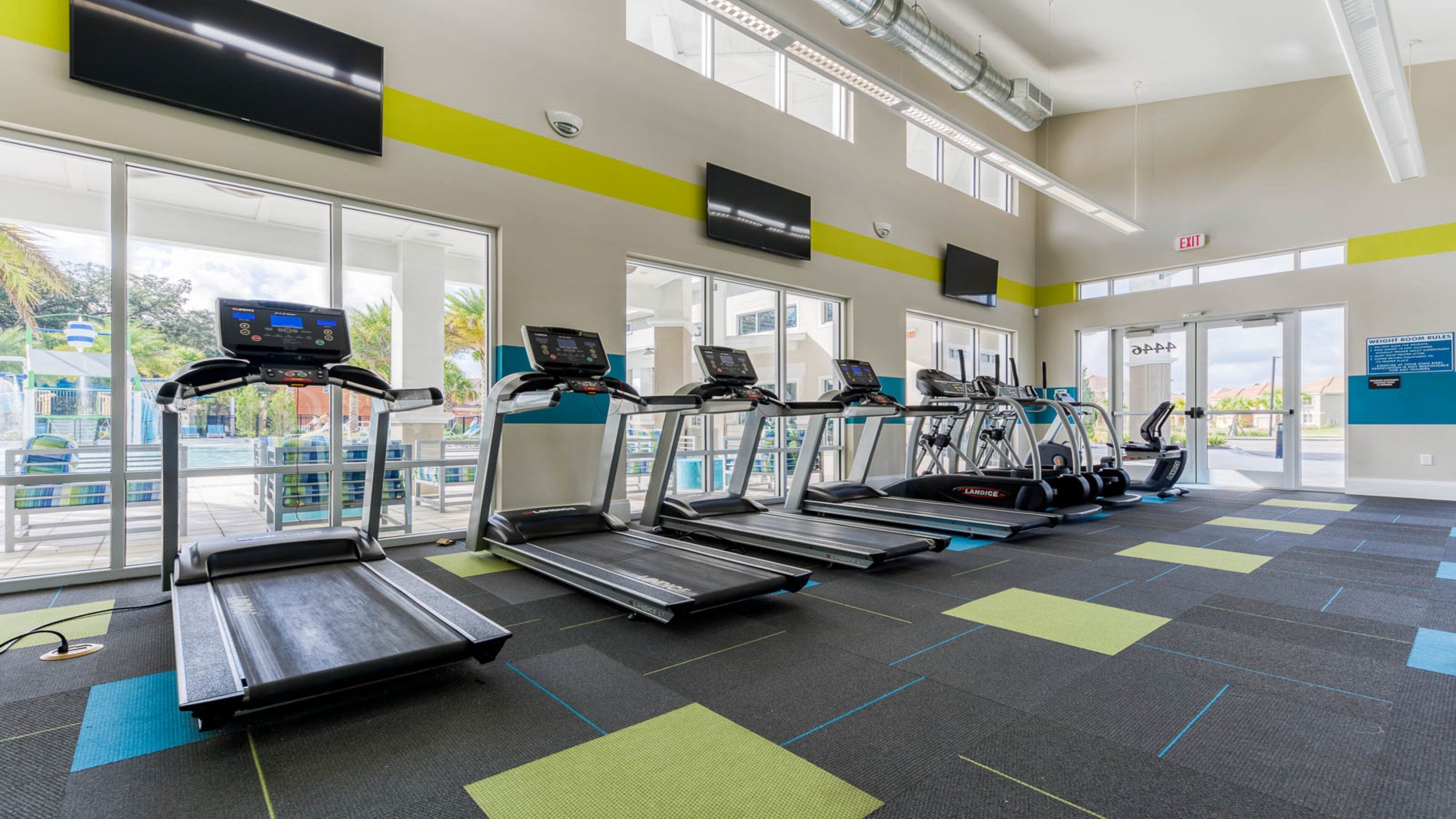 A gym with treadmills, weight machines, and a large window providing a view of the outdoors.