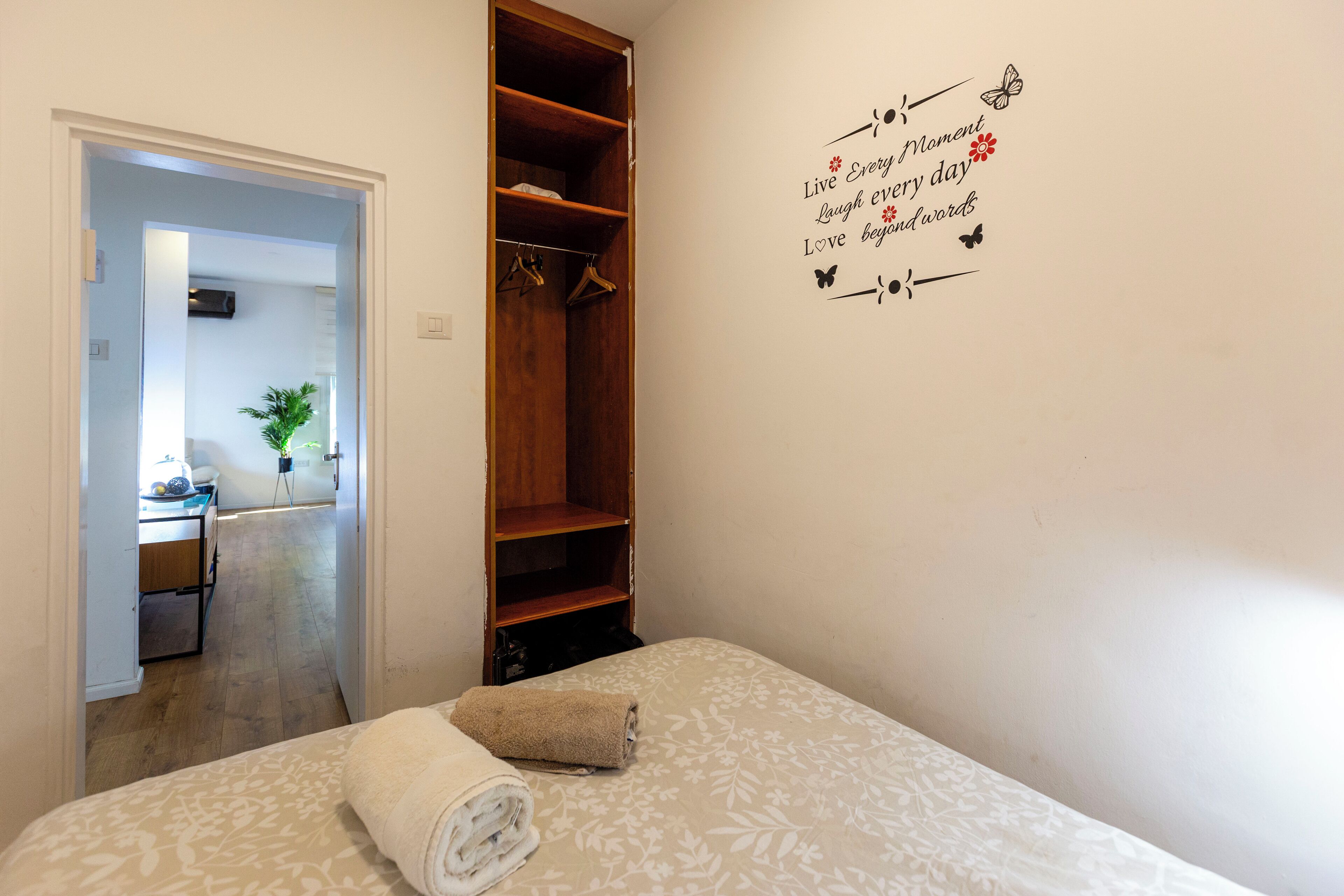 Ein Schlafzimmer mit einem Bett, einem Holzschrank und einer Wand mit motivierenden Sprüchen.