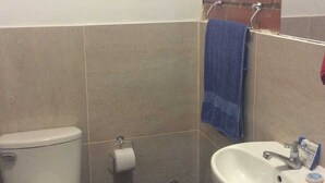 Ein kleines Badezimmer mit Toilette, Waschbecken und Mülleimer.