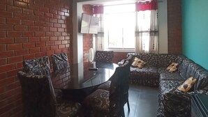 Ein Essbereich mit Backsteinwand, rundem Tisch und gemusterten Sofas.