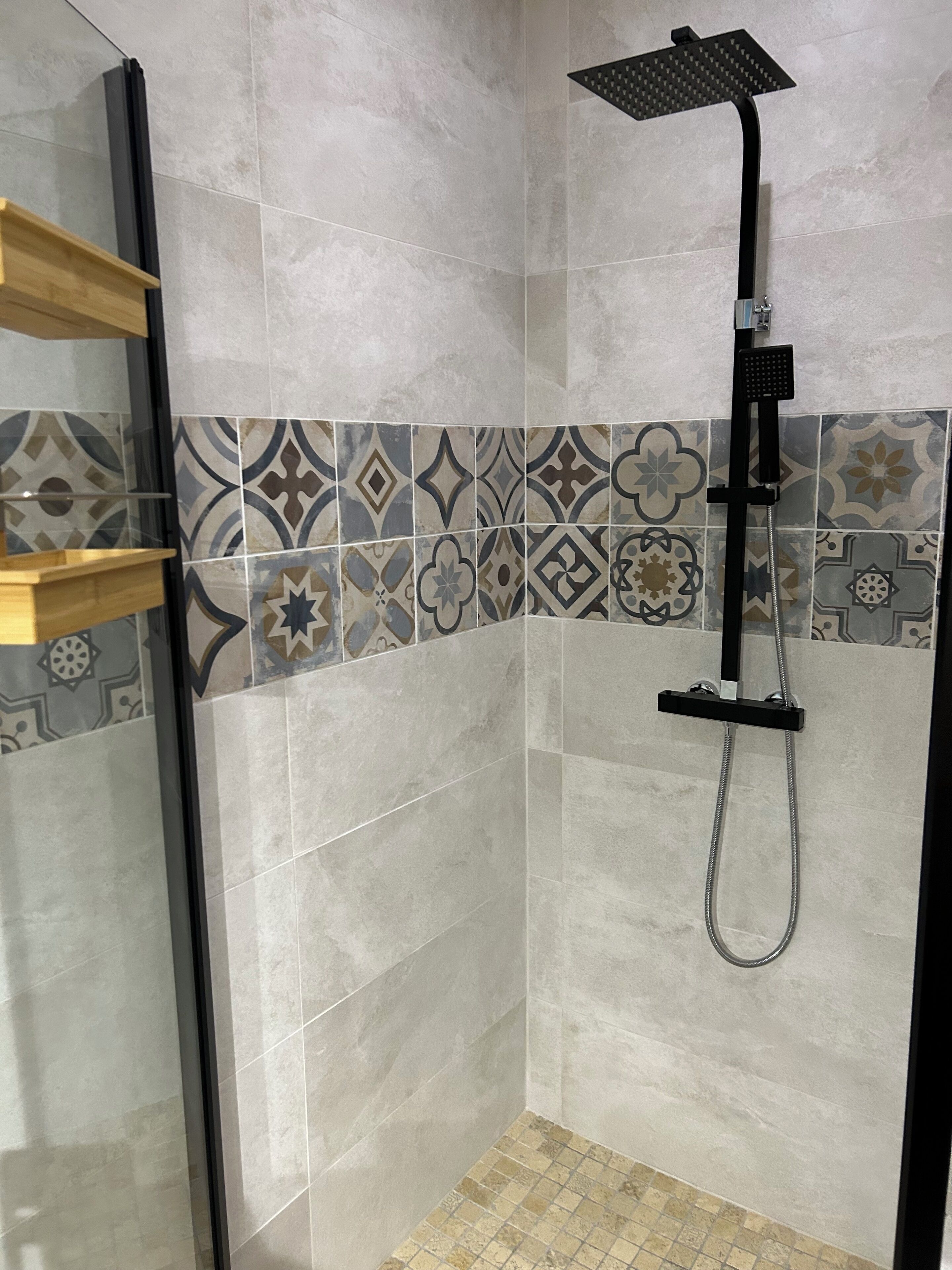 Un espace douche équipé d’un pommeau de douche à main et d’une porte en verre.