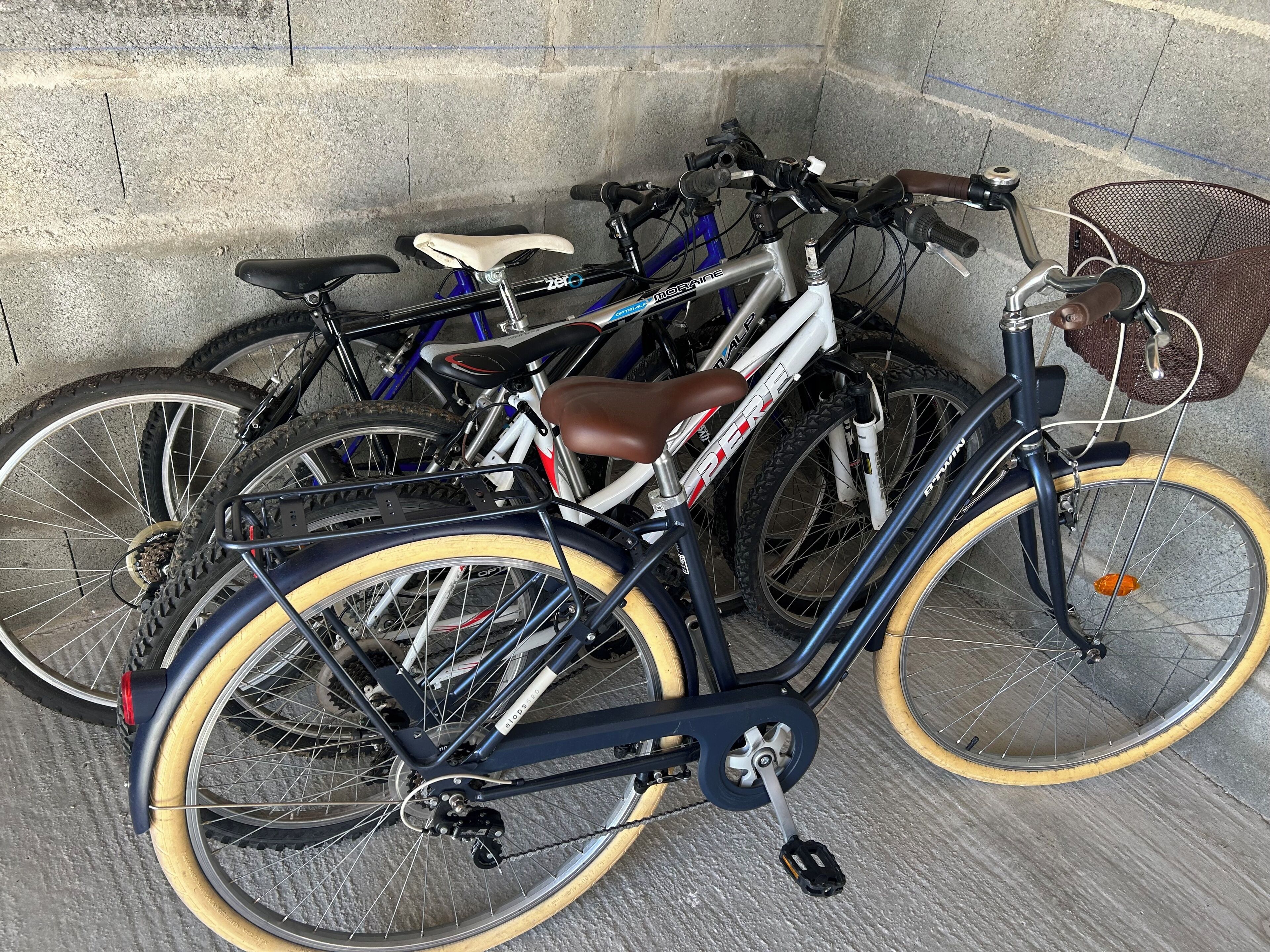 Un aparcaciclos con varias bicicletas estacionadas junto a un muro de hormigón.