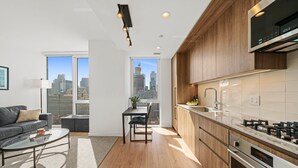 Une cuisine moderne avec des meubles en bois, une cuisinière en acier inoxydable et une grande fenêtre donnant sur la ville.