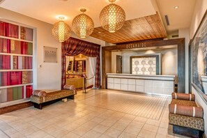Un vestíbulo de hotel con mostrador de recepción, asientos con diseño y iluminación decorativa.