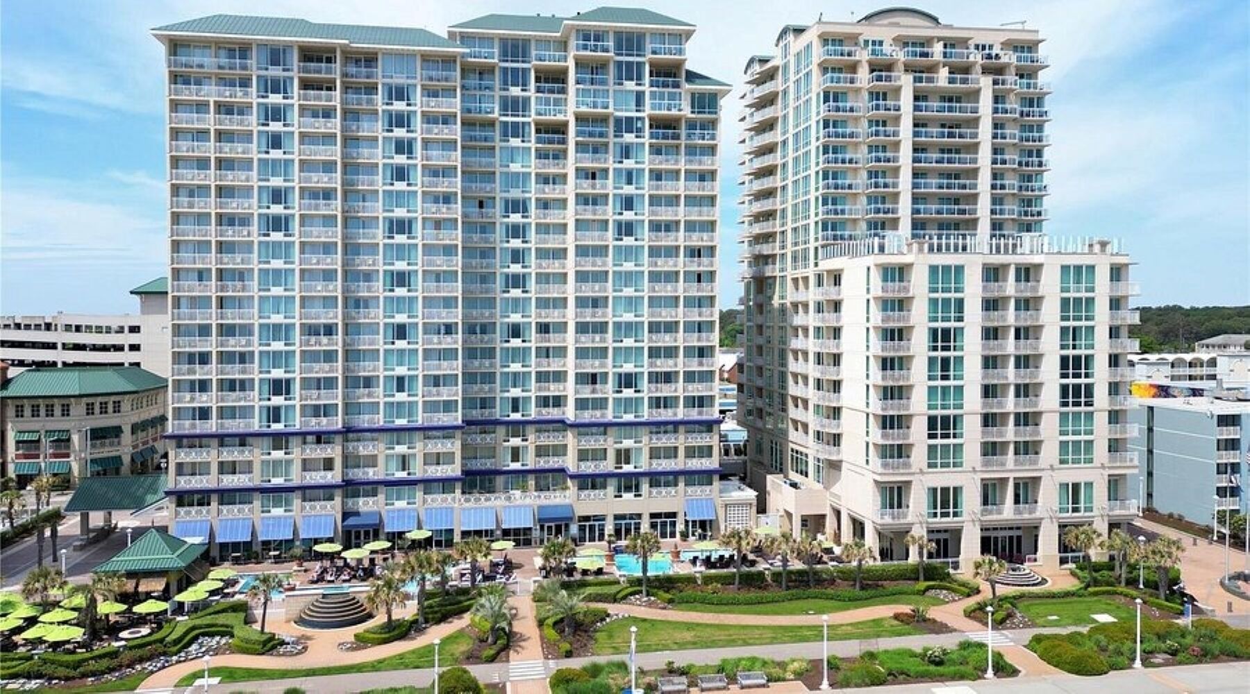 A high-rise hotel with multiple balconies, a swimming pool, and a landscaped courtyard.