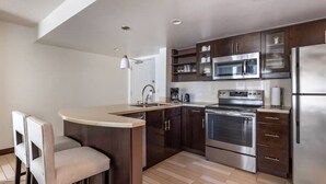 A modern kitchen with a central island, stainless steel appliances, and dark wood cabinetry.