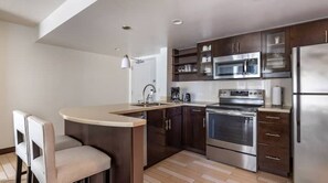 A modern kitchen with a central island, stainless steel appliances, and dark wood cabinetry.
