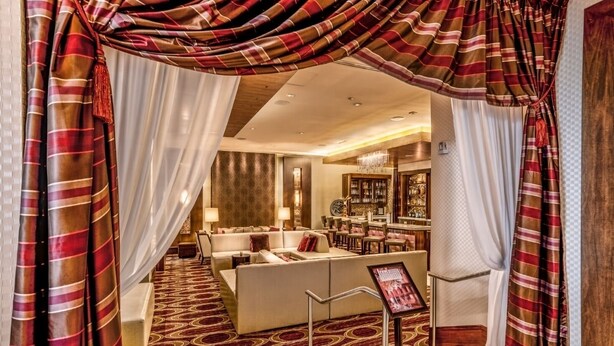 A hotel lobby with a seating area, a bar, and a view of the bar area.