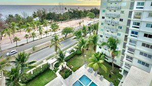 Un hotel moderno con piscina, palmeras y vistas a la playa y al océano.