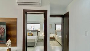 Habitación de hotel con cama, mesita de noche, lámpara y vistas de la ciudad.