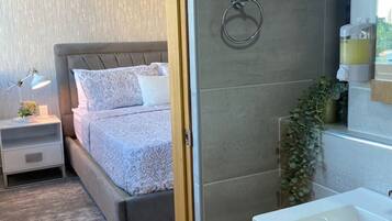 A modern bedroom with a large bed, bedside tables, and a nightstand.