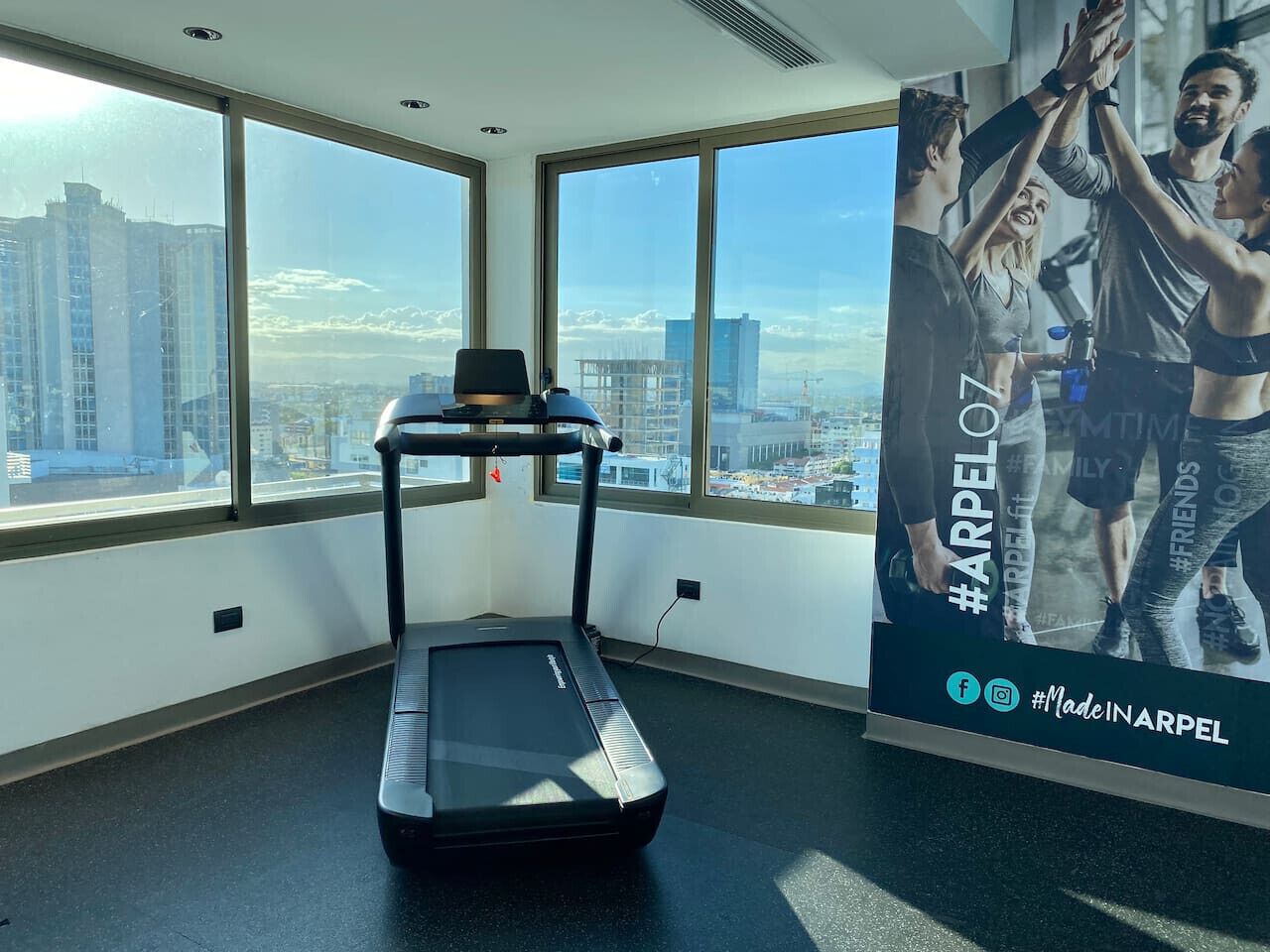 A treadmill in a room with large windows offering a city view.