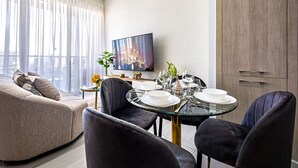 Ein modernes Wohnzimmer mit einer Couch, einem Esstisch für vier Personen und einem an der Wand befestigten Flachbildfernseher.