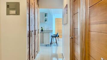 A hallway with wooden doors, a tiled floor, and a kitchen area visible in the distance.