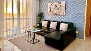 Ein modernes Wohnzimmer mit einer Couch, einem Couchtisch und einem großen Fenster mit transparenten Vorhängen.