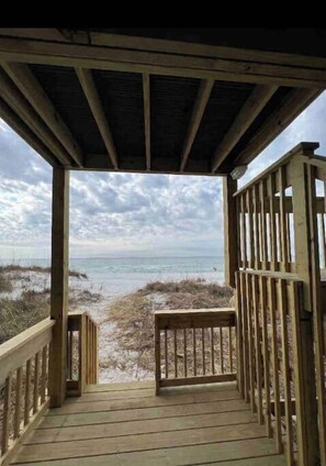 Enjoy the serene beach view from this expansive deck, offering a path to the sandy shore.