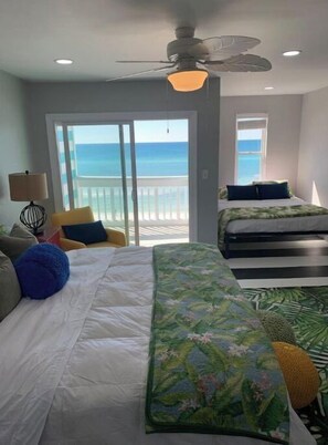 Relax in this serene ocean-view room with a large bed, ceiling fan, and sliding glass door.