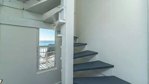 A staircase with a view of the sea through a window. - Sunrise, Sunburn, Sunset, Repeat (Destin)