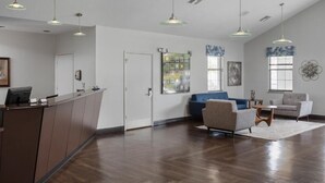 A spacious lobby with a reception desk, seating area, artwork, and pendant lighting.