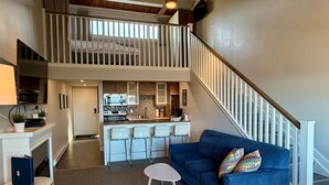 A modern living space with a loft bedroom, a kitchen, a dining area, and a staircase. - Oceanfront Studio with Loft - amazing views! (Qualicum Beach)