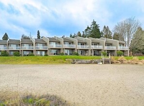 A multi-story hotel with a flat roof, located near a sandy beach. - Oceanfront Studio with Loft - amazing views! (Qualicum Beach)