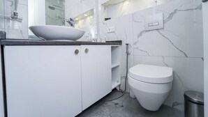 A modern bathroom with a white sink, toilet, and marble walls. - Luxury apartment on av. Melikishvili with huge balcony, city center  (T'bilisi)
