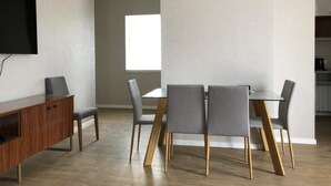 A modern dining area with a wooden table and grey upholstered chairs, a wooden cabinet, and a flat-screen TV mounted on the wall. - Luxury apartment on av. Melikishvili with huge balcony, city center  (T'bilisi)