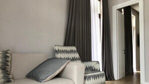 A living room with a beige sofa, patterned pillows, and a wooden floor. - Luxury apartment on av. Melikishvili with huge balcony, city center  (T'bilisi)