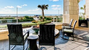 Eine Terrassengruppe im Freien mit Korbstühlen, einer kleinen Feuerstelle und Blick aufs Meer.