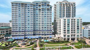 A high-rise hotel with multiple balconies, a swimming pool, and a landscaped courtyard.