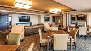 A hotel lobby with a billiards table, seating area, and a bar/lounge with televisions.