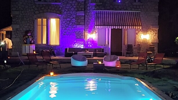 Un edificio de piedra con piscina y zona de estar al aire libre.