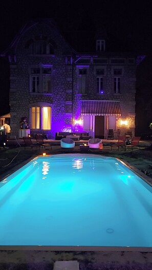 Un edificio de piedra con piscina y zona de estar al aire libre.