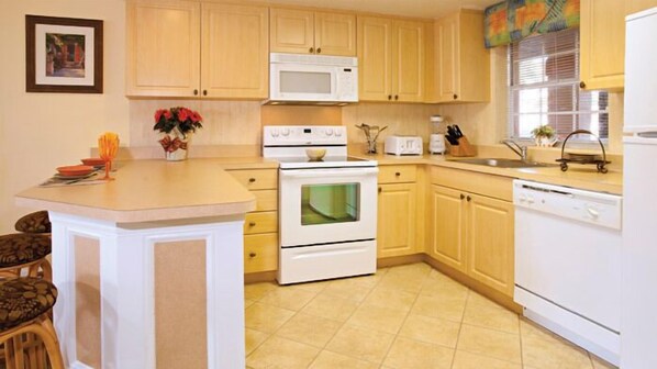 Una cocina con armarios de madera, microondas, estufa y lavavajillas.