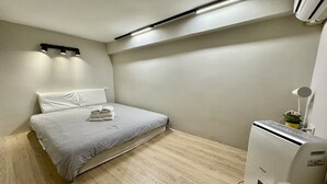 A small, clean room with a bed, a bedside table, a lamp, and a heater. - Liu-He 914 Hostel (Kaohsiung)