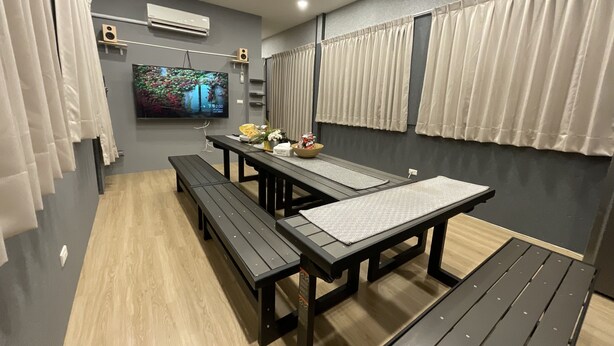 A modern room with a long table, benches, and a flat-screen TV mounted on the wall. - Liu-He 914 Hostel (Kaohsiung)