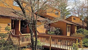A wooden cabin with a porch, a small window, and a lamp post.