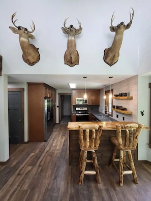 A modern kitchen with wooden cabinets, a central island, and rustic deer antlers mounted on the wall.
