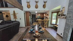 Un comedor espacioso con una mesa y sillas de madera, un ventilador de techo y monturas de animales en la pared.