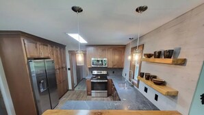 Una cocina moderna con armarios de madera, electrodomésticos de acero inoxidable y una isla central.
