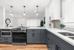 Enjoy cooking in this sleek kitchen with a stainless steel range hood, sink, and modern cabinetry.