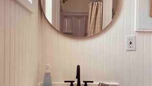 Une salle de bain avec un miroir rond, un lavabo et une serviette.
