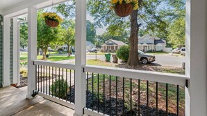 Une véranda avec des balustrades blanches et des jardinières suspendues.