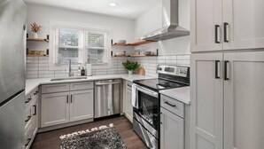 Une cuisine moderne avec des meubles blancs, des appareils en acier inoxydable et un tapis noir et blanc.