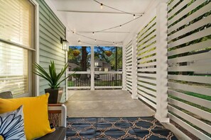 A covered porch with a bench, a potted plant, and a view of the neighborhood.