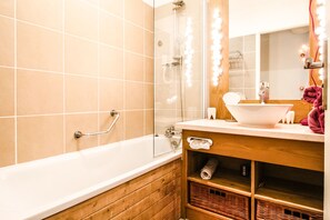 A bathroom with a bathtub, a glass-enclosed shower, a vanity with a mirror, and a towel rack. - Beautiful 2-bed Family Apartment, Flaine Montsoleil (Flaine)