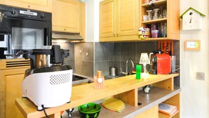 Een keuken met houten kastjes, een zwarte oven, een koffieapparaat en een groene kom op het aanrecht.